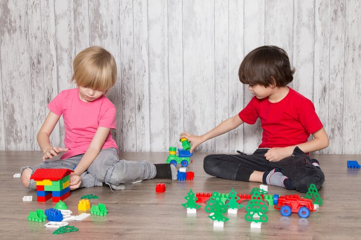 two-cute-boys-pink-red-t-shirts-playing-with-toys_179666-1380